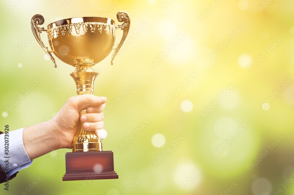 Hand holding golden trophy on background