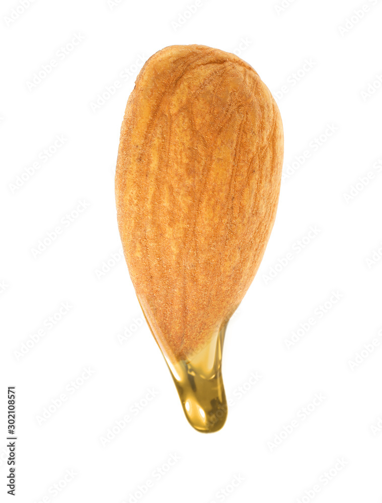 Oil dripping from almond against white background