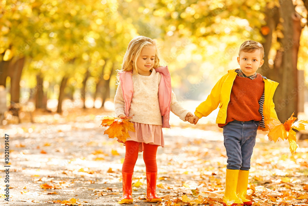 Cute little children with leaves in park on autumn day