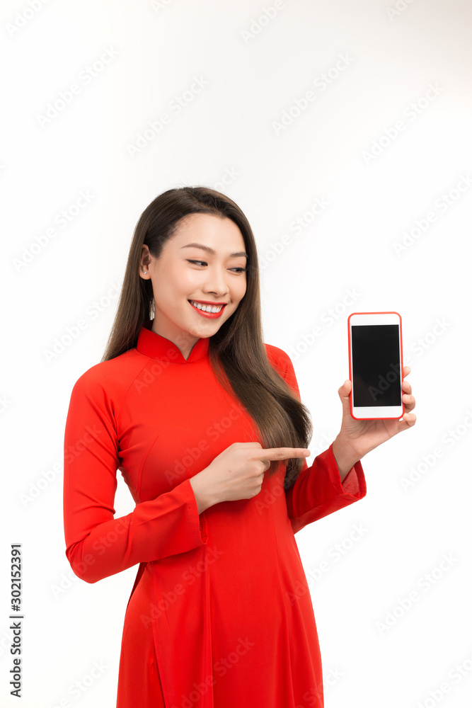 Portrait of a joyful asian woman showing blank screen mobile phone isolated over white background