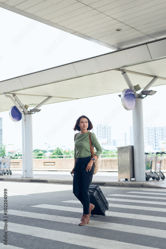 The girl is on the road with a suitcase on a pedestrian crossing