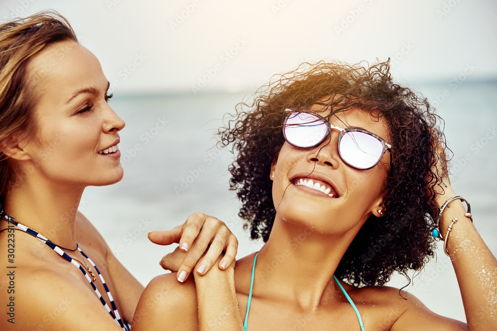 Smiling young women wearing bikinis standing on a tropical beach