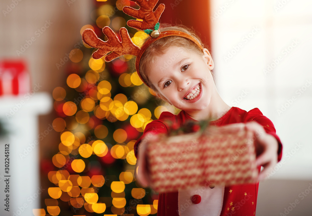 happy laughing child girl with christmas present at home.