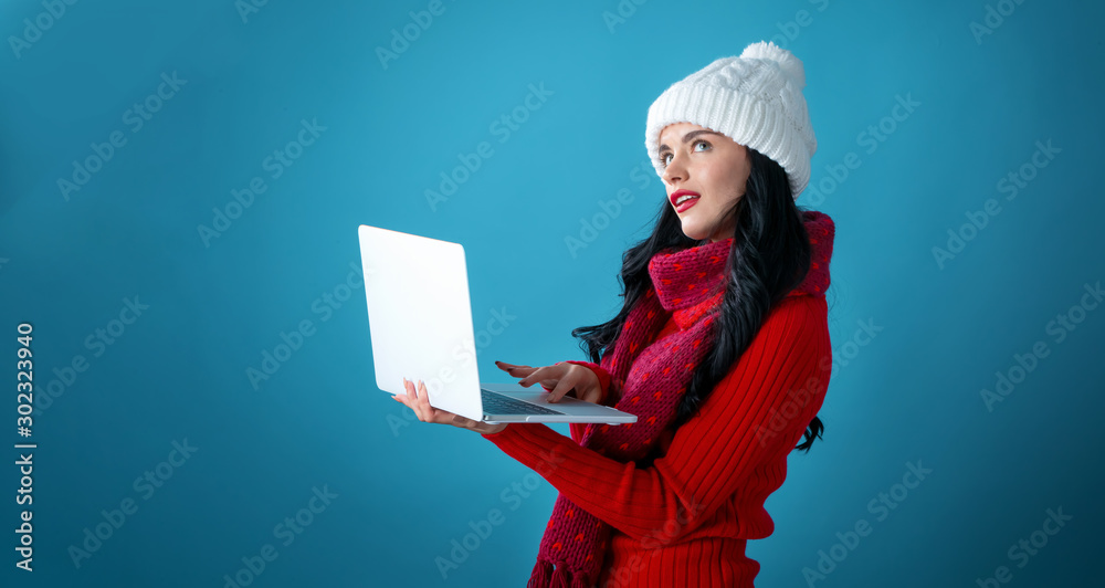 Young woman with a laptop computer holding a Christmas gift box on a dark blue background