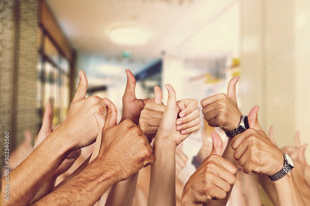 Hands gesturing thumbs up on blurred background