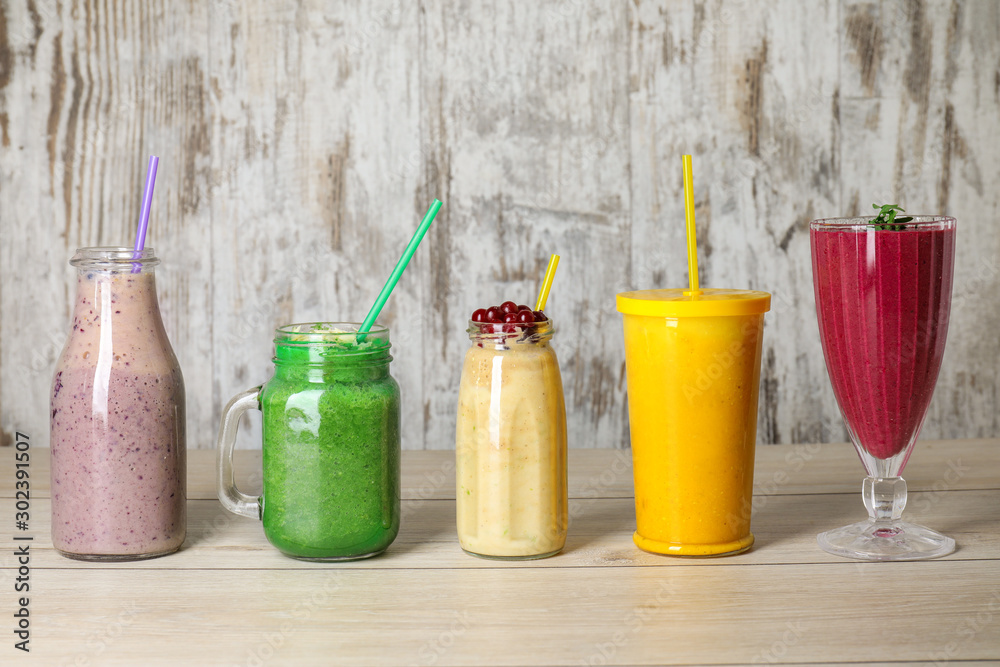 Glassware with different healthy smoothie on table