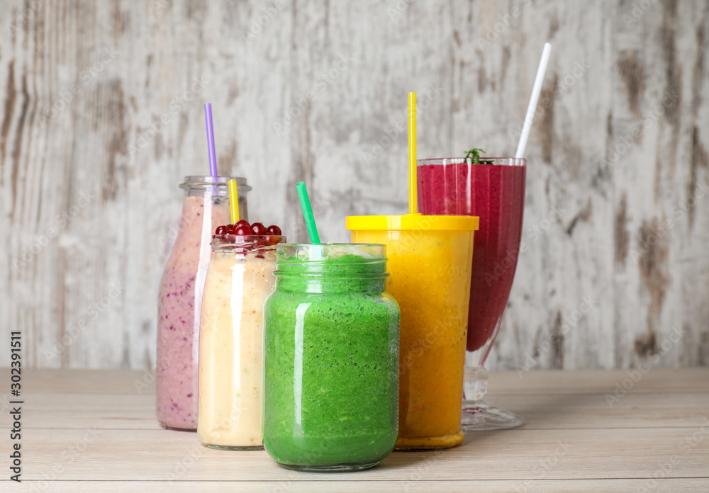 Glassware with different healthy smoothie on table