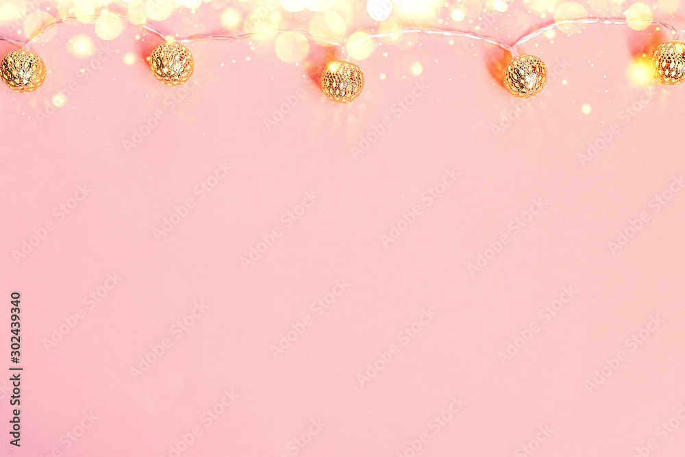 top view of a garland and lights on a pink background. christmas background