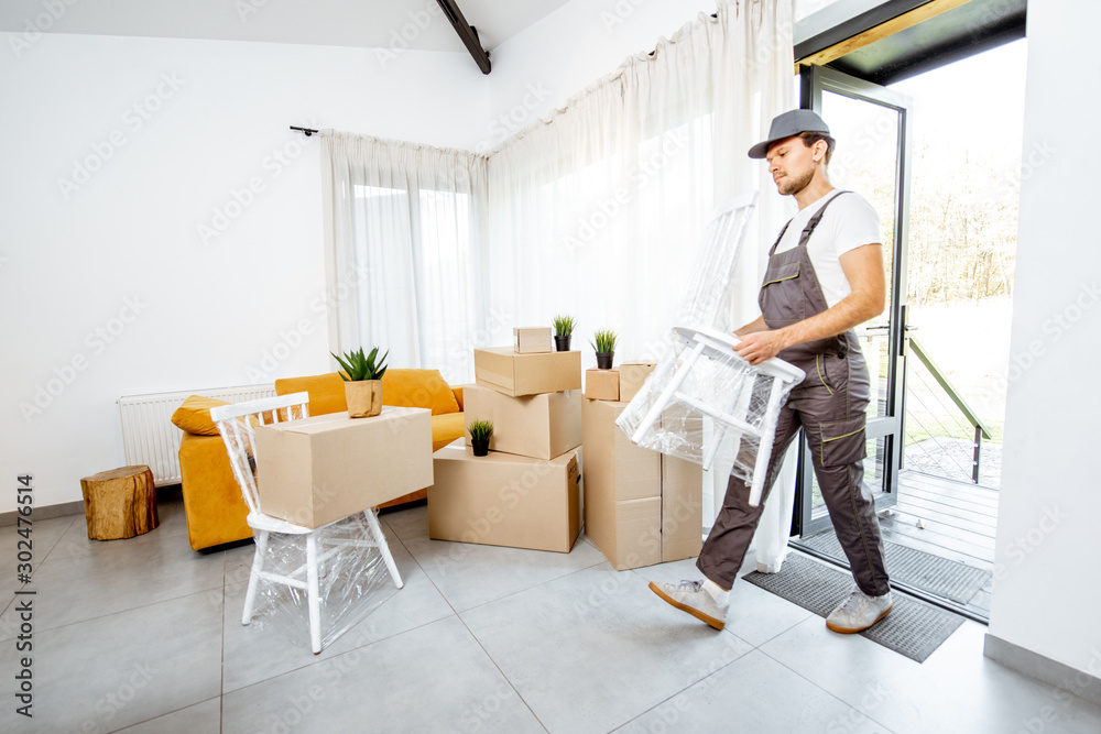 Handsome mover in workwear performing professional delivery of a goods and furniture during relocati