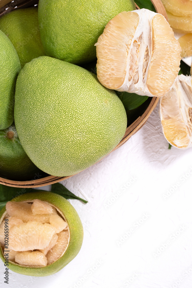 Fresh pomelo, pummelo, grapefruit, shaddock on white cement background in bamboo basket. Autumn seas