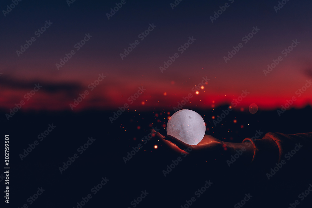 moon on the palm with sparks around on sunset background