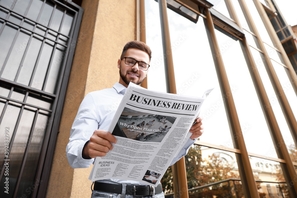 Handsome man with newspaper outdoors