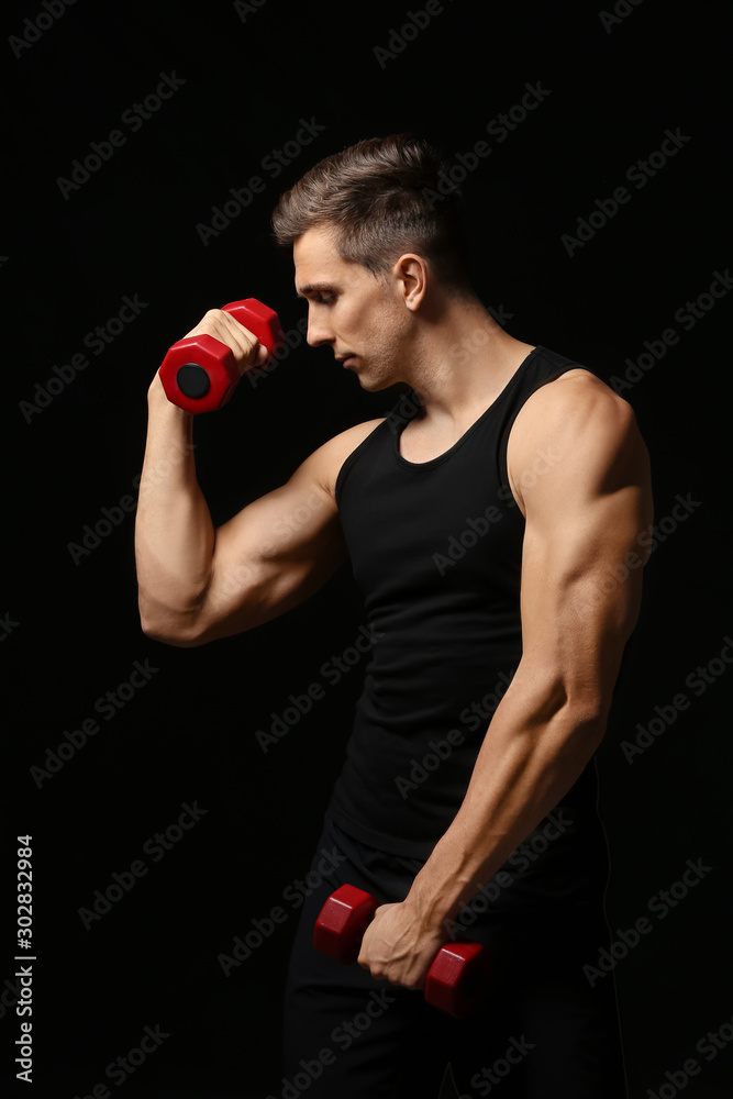 Sporty young man with dumbbells on dark background