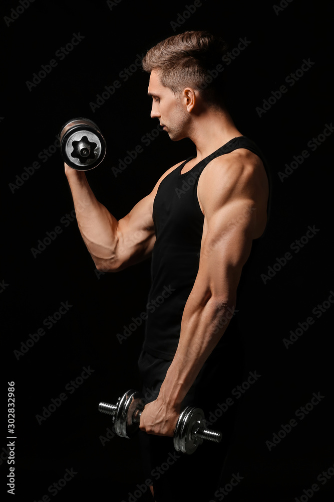 Sporty young man with dumbbells on dark background