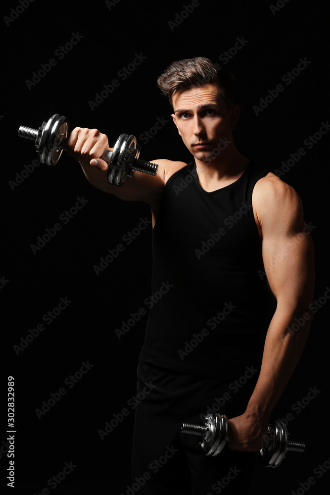 Sporty young man with dumbbells on dark background