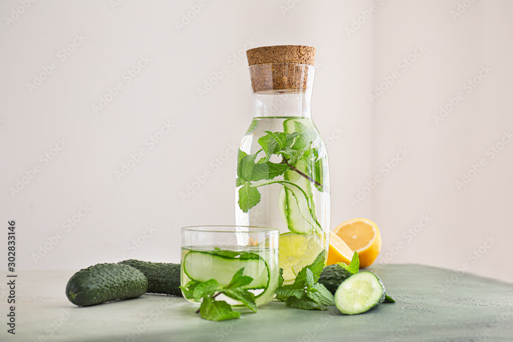 Glass and bottle of healthy infused water on light background