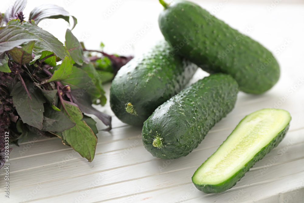 Fresh cucumbers with basil on board, closeup