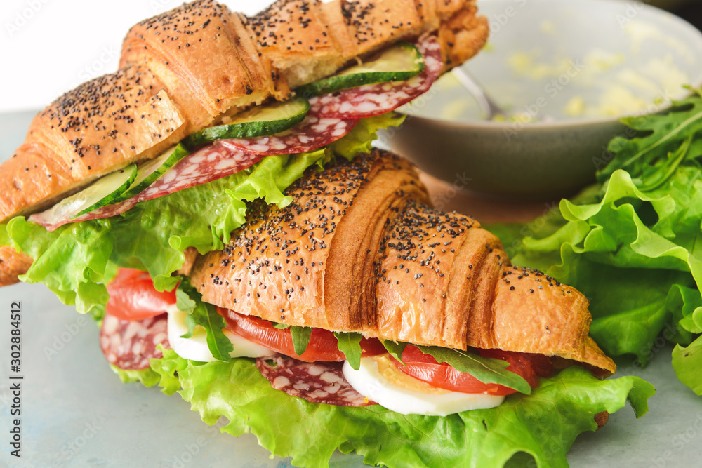 Tasty croissant sandwiches on table