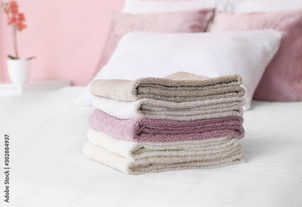 Stack of soft clean towels on bed