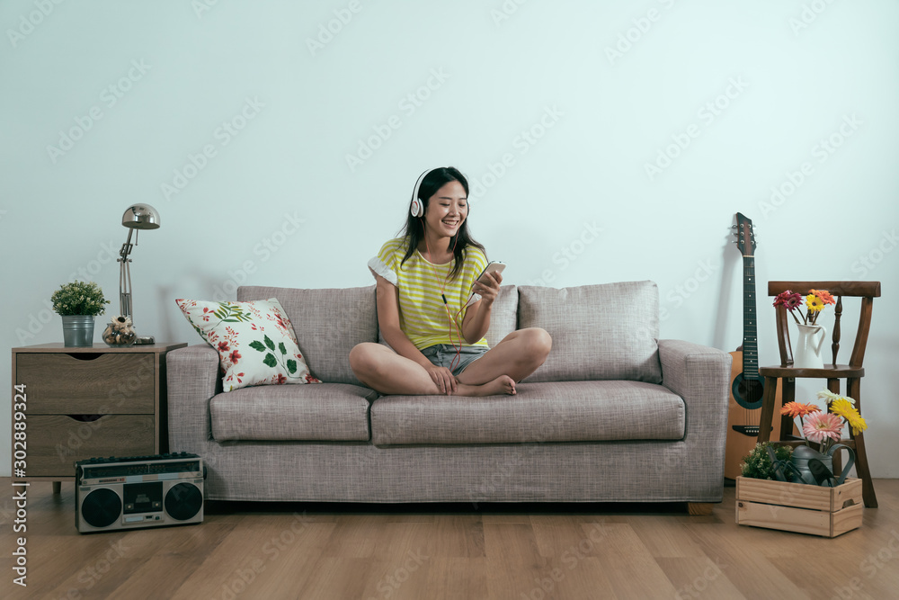 Pleased asian japanese girl wearing trendy summer shorts chilling on sofa enjoy morning. smiling cut