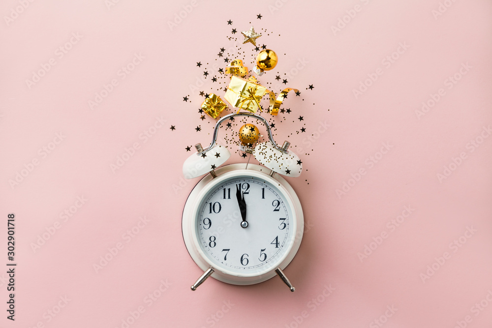 Christmas or New Year composition on pink background with retro alarm clock and Christmas decoration