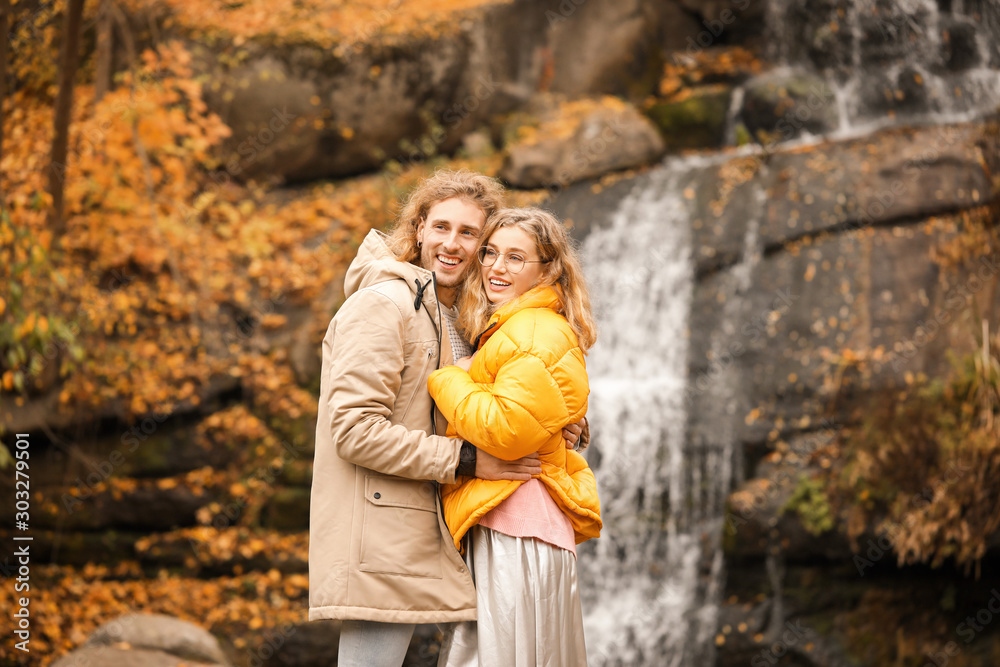 Young couple near waterfall in park on autumn day