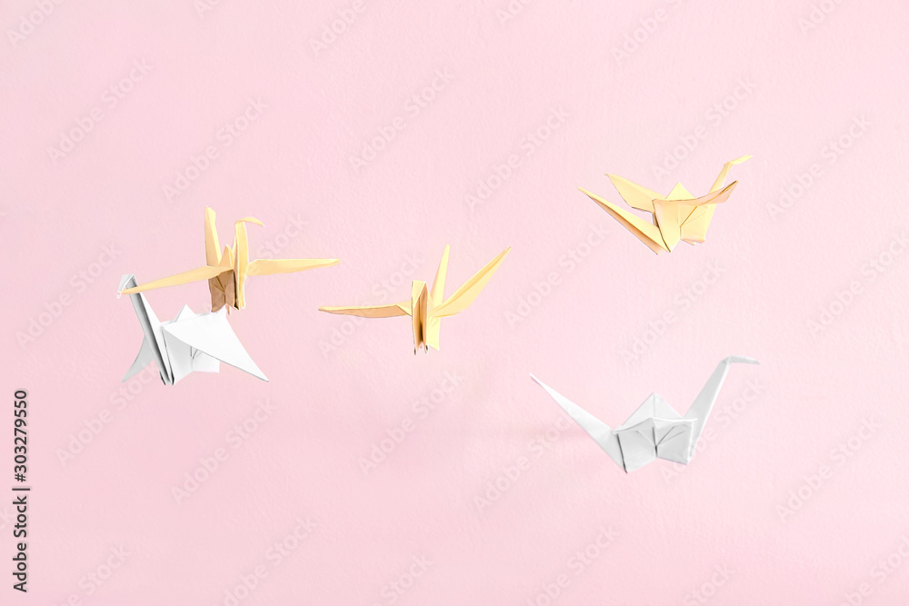 Origami cranes on color background