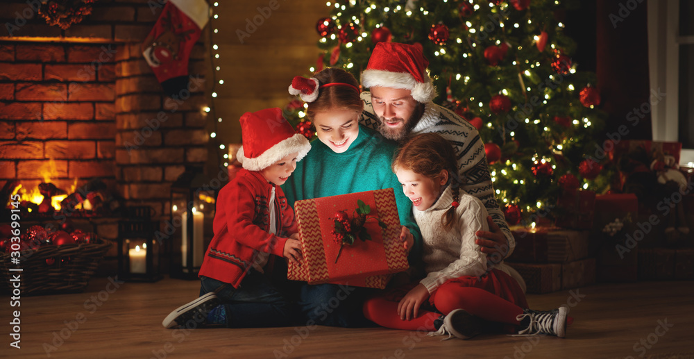 Merry Christmas! happy family mother father and children with magic gift near tree   at home.