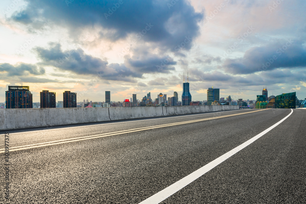 Empty asphalt highway and modern cityscape in Shanghai at sunset.