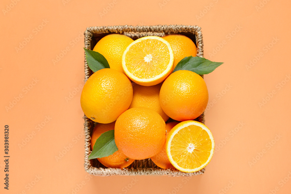 Basket with fresh oranges on color background