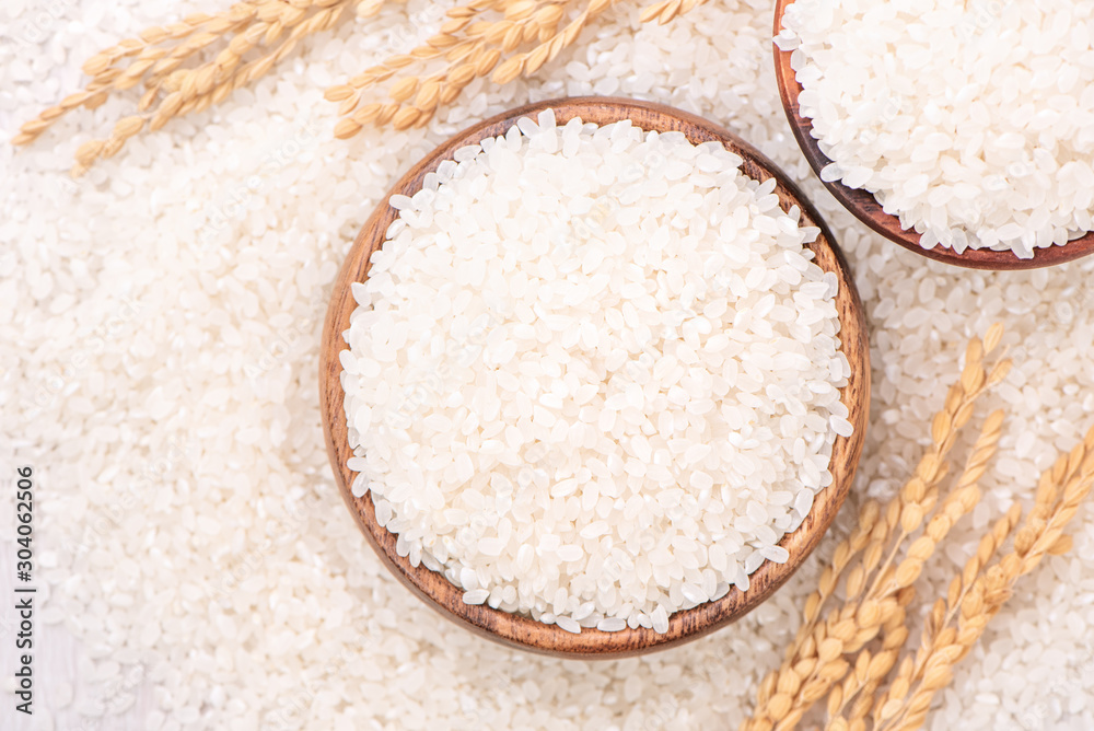 Raw white polished milled edible rice crop on white background in brown bowl, organic agriculture de