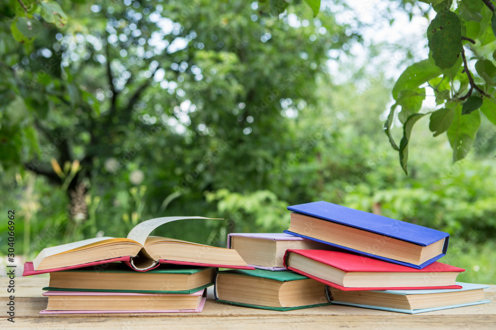 Studying in summer concept. Open book on a wooden table in a garden, sunny summer day