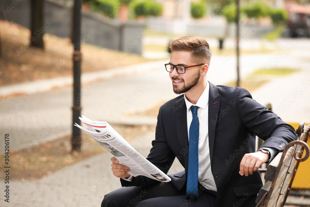 Handsome businessman with newspaper outdoors