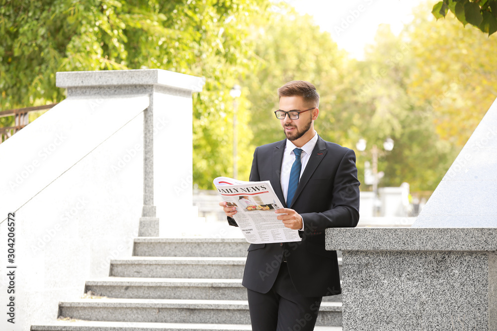 Handsome businessman with newspaper and coffee outdoors