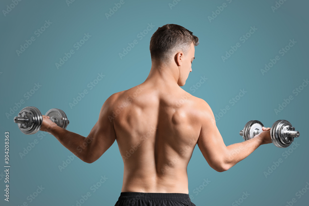 Handsome male bodybuilder with dumbbells on grey background