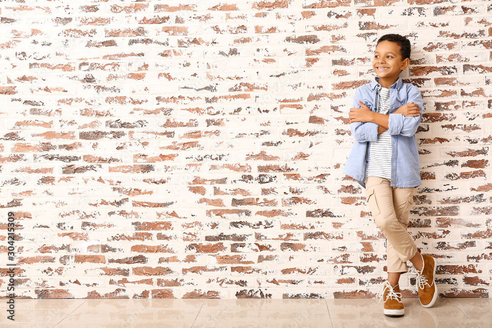 Fashionable African-American boy near brick wall