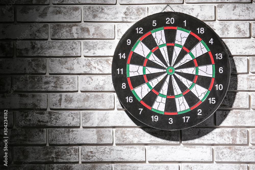 Dartboard hanging on dark brick wall