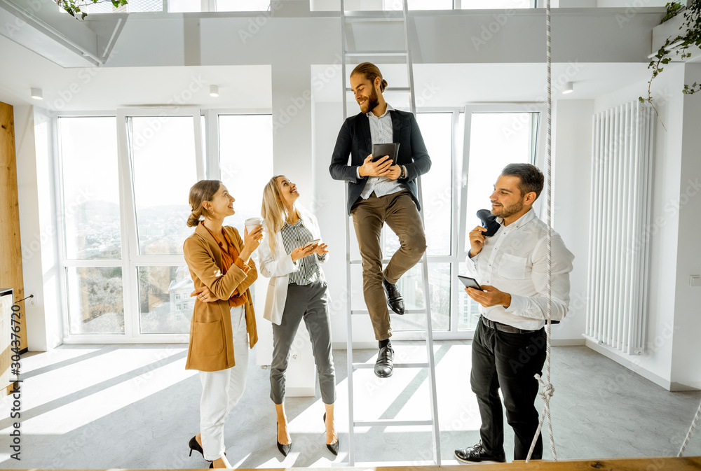 Group of a young creative office employees having some informal discussion, while standing together 