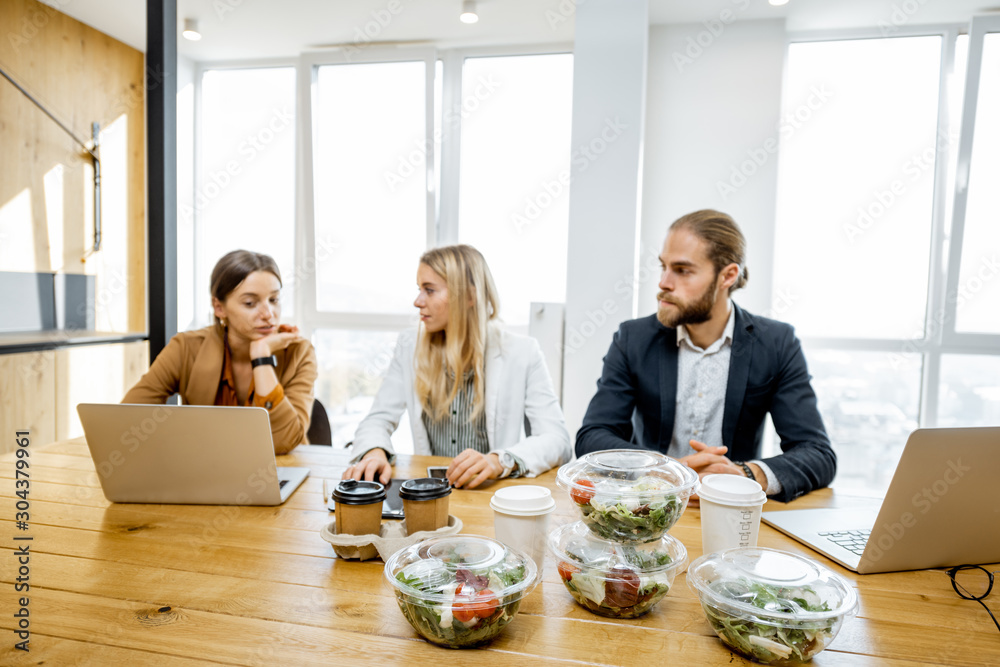 Office workers sitting in the office with business lunches on the foreground. Concept of healthy tak