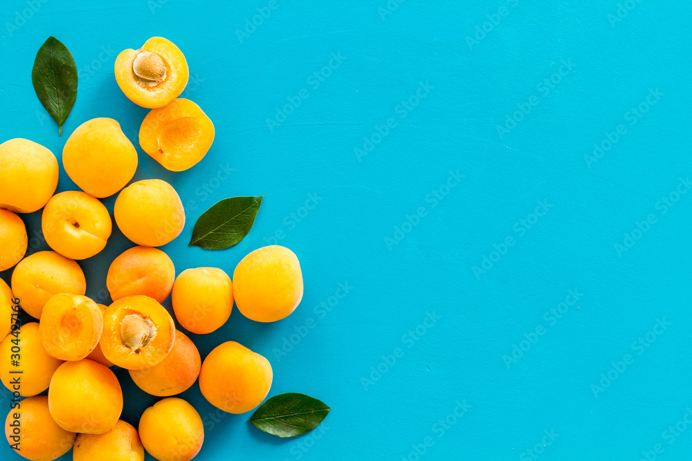 Fruit frame. Apricots and leaves on blue background top view copy space