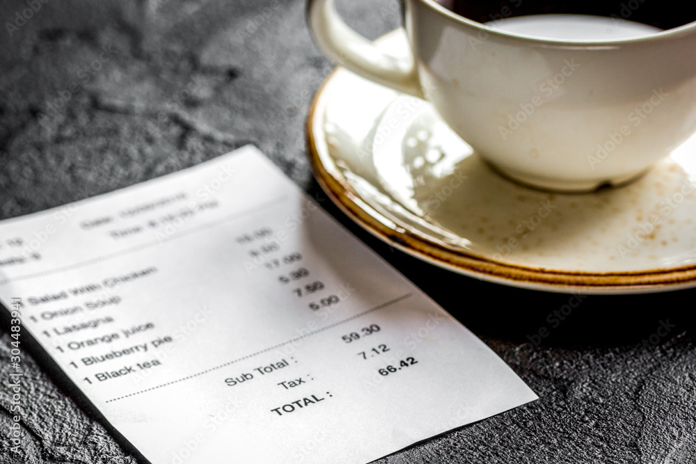 restaurant bill, card and coffee on dark table background