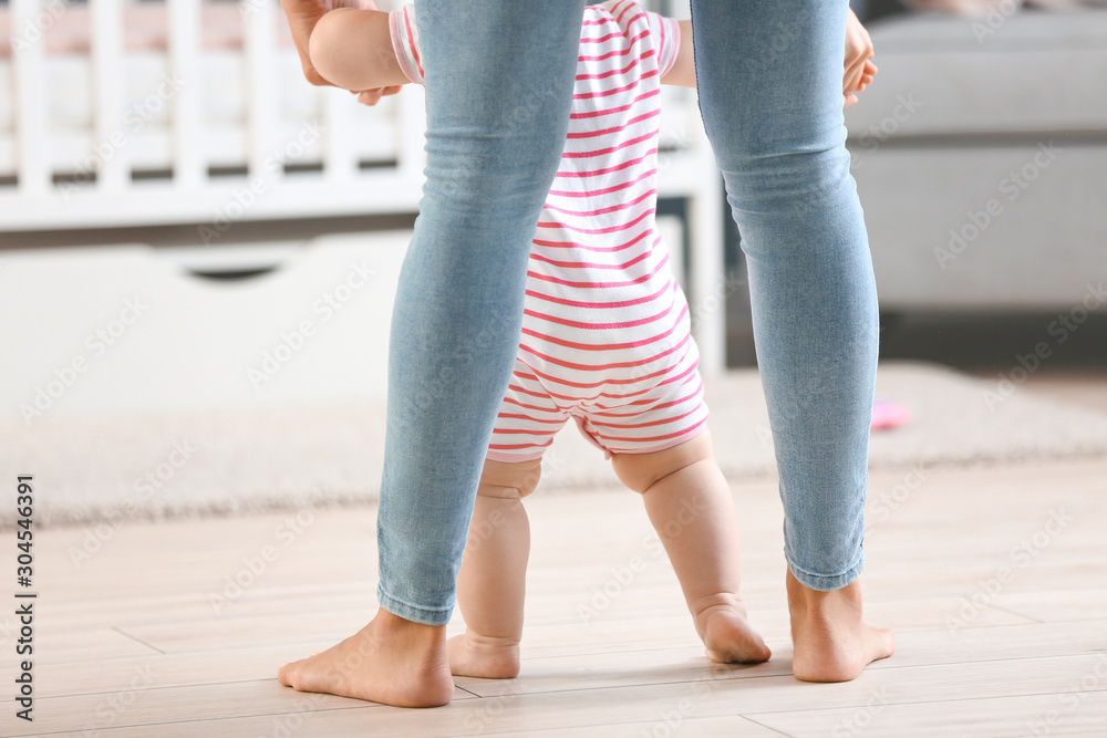 Mother teaching her little baby to walk at home