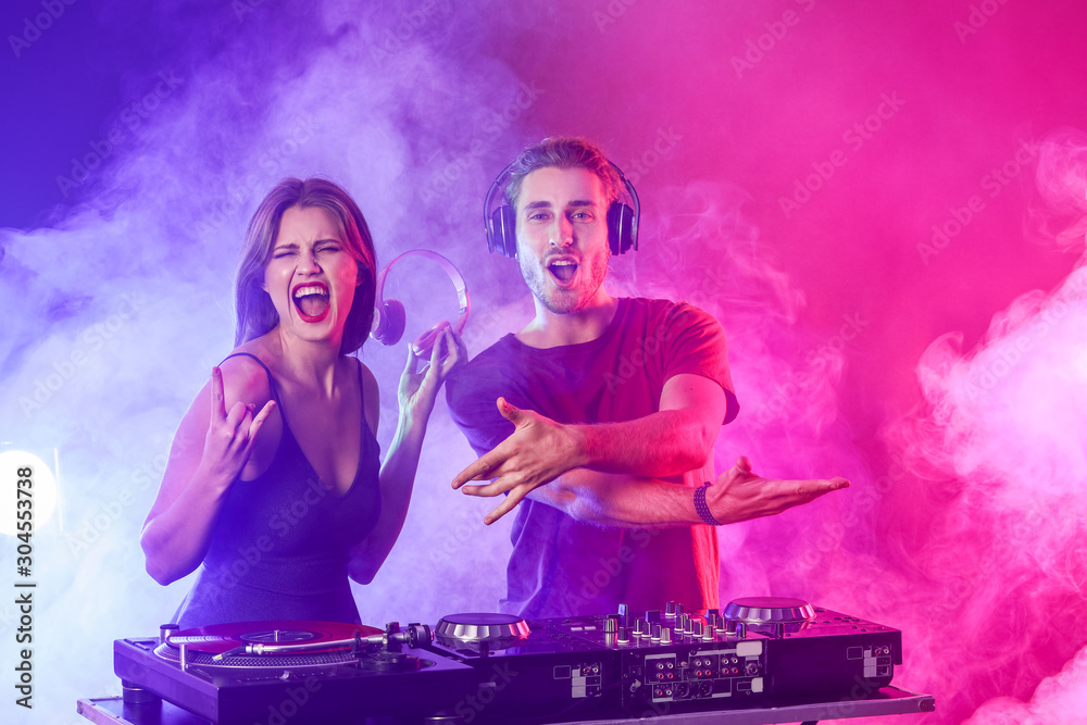 Young djs playing music in nightclub