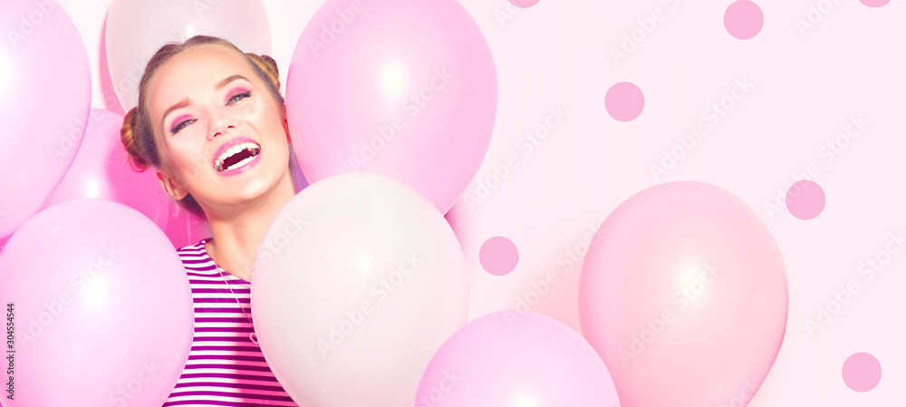 Beauty girl with colorful air balloons laughing over pink background. Beautiful Happy Young woman on