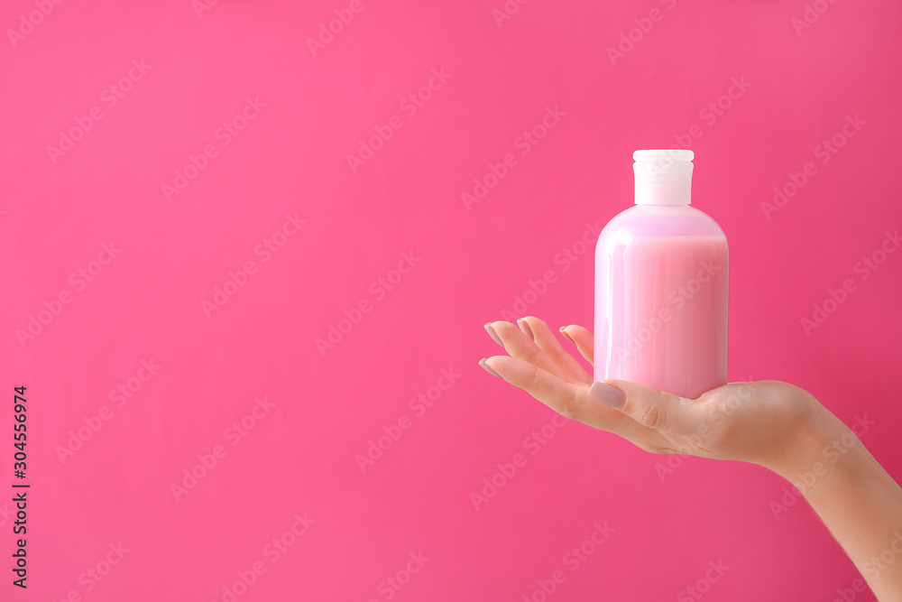 Female hand with cosmetic product in bottle on color background