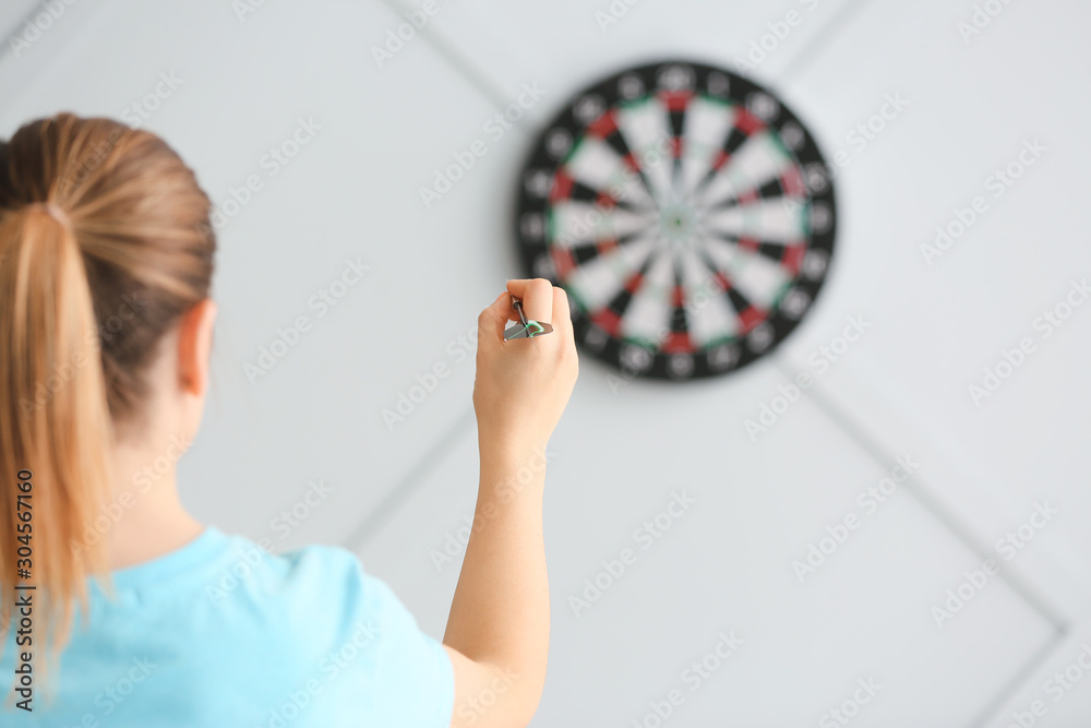 Young woman playing darts indoors