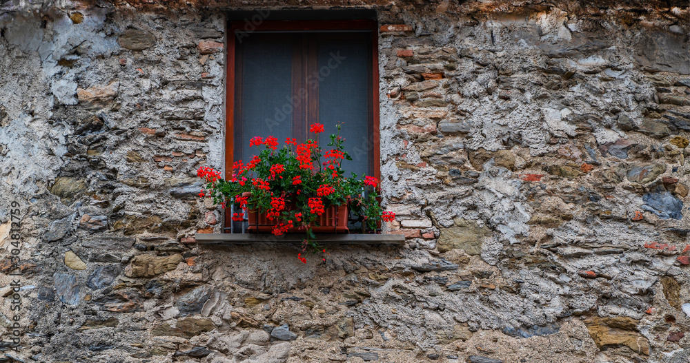 Old building in italian village. Stone wall with windows and flowers. Building with beautiful old ar