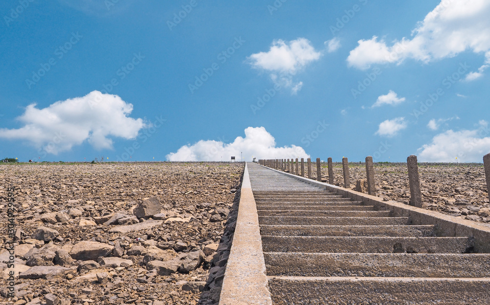 Long brick staircase with side stone have destination have bride and groom. Blue sky and white cloud