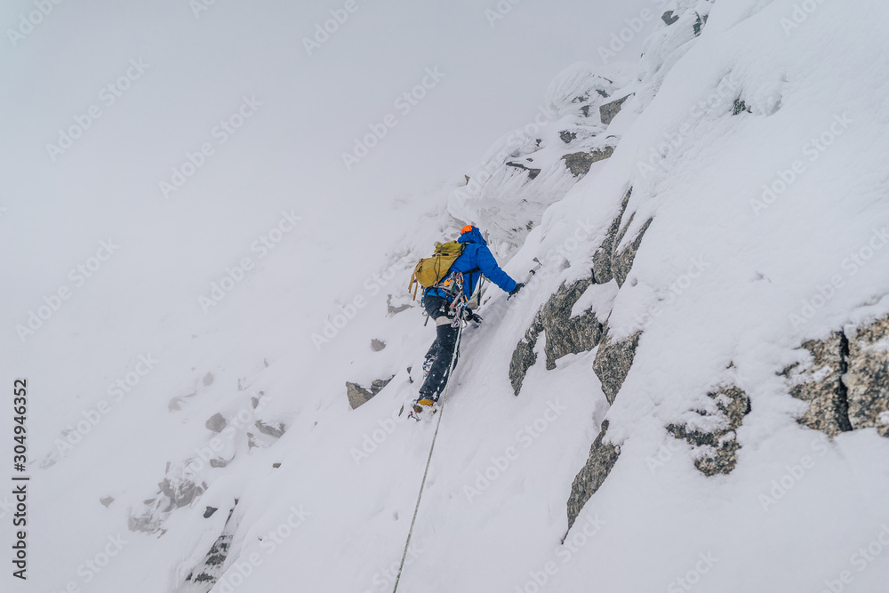 一名登山运动员在冬季极端条件下攀登高山山脊。冒险攀登高山i峰