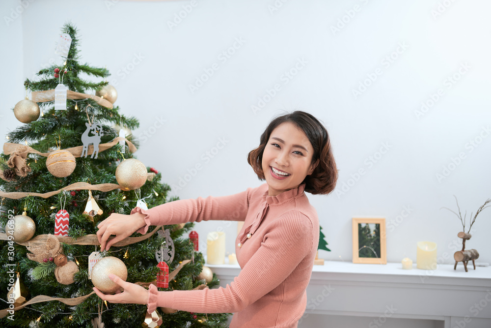 美丽的年轻女人装饰圣诞树，装饰圣诞树